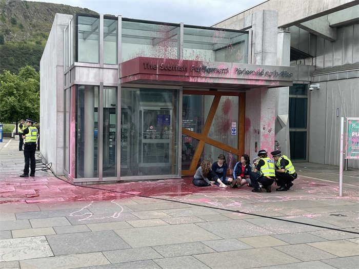 Climate activists This Is Rigged cover Scottish Parliament entrance in red paint